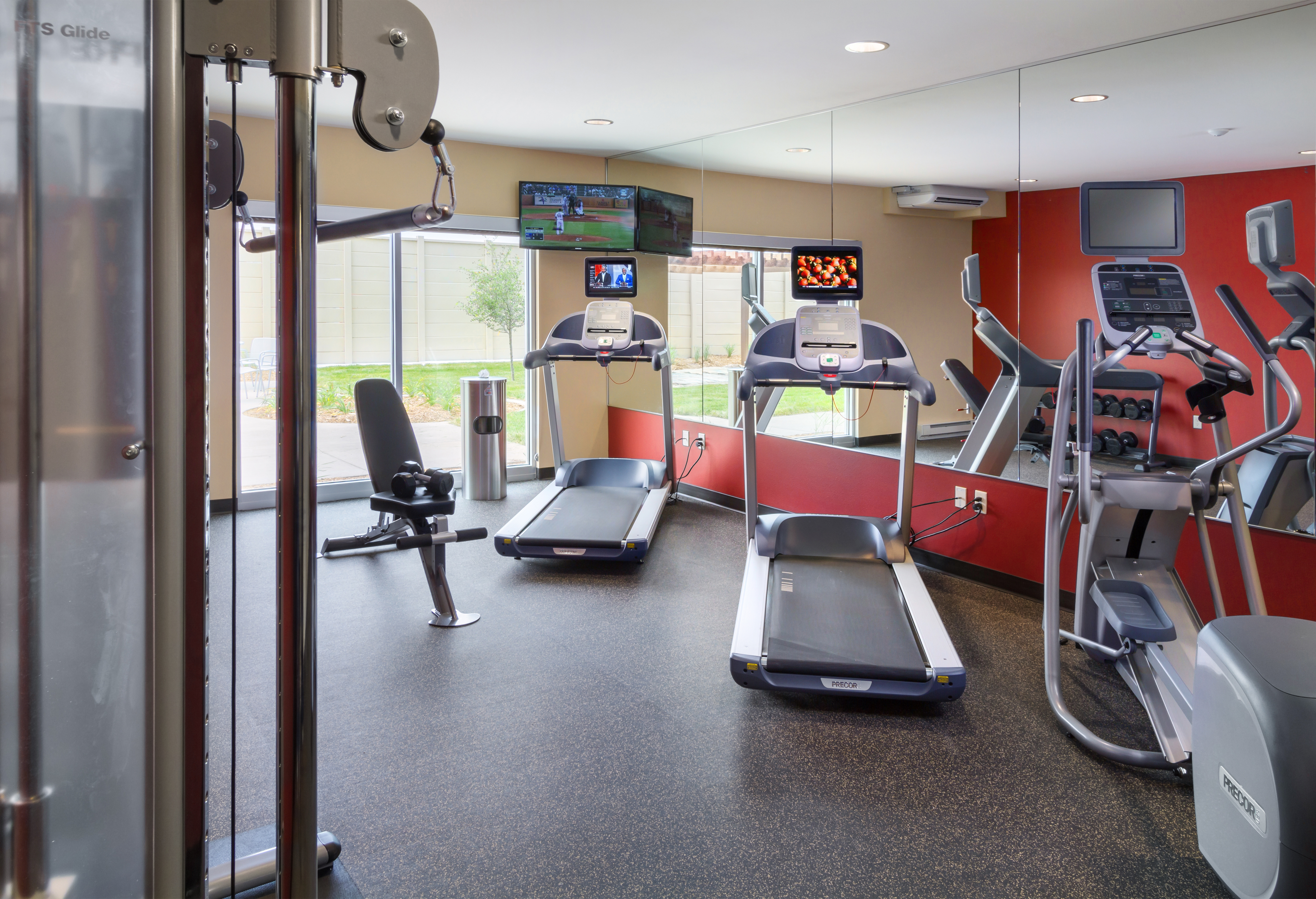 A gym featuring two treadmills, an elliptical, and a weight bench.